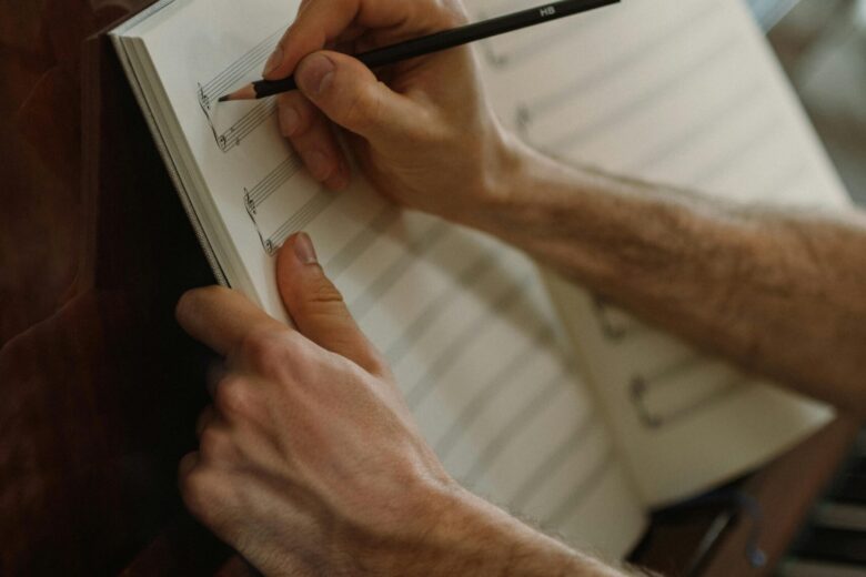 A person composing music with pencil and sheet on a piano. Captures artistic creativity.