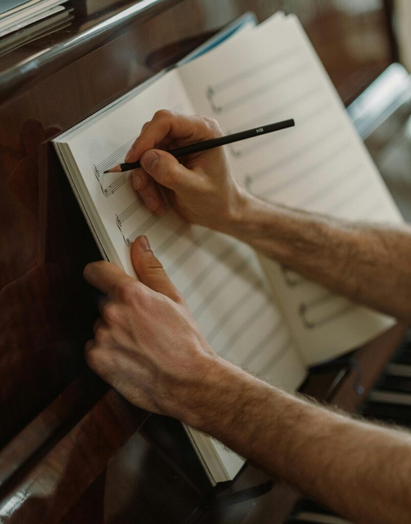 A person composing music with pencil and sheet on a piano. Captures artistic creativity.